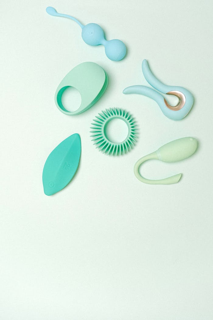 A variety of elegantly designed silicone sex toys on a soft pastel green background, showcasing modern minimalist aesthetics.