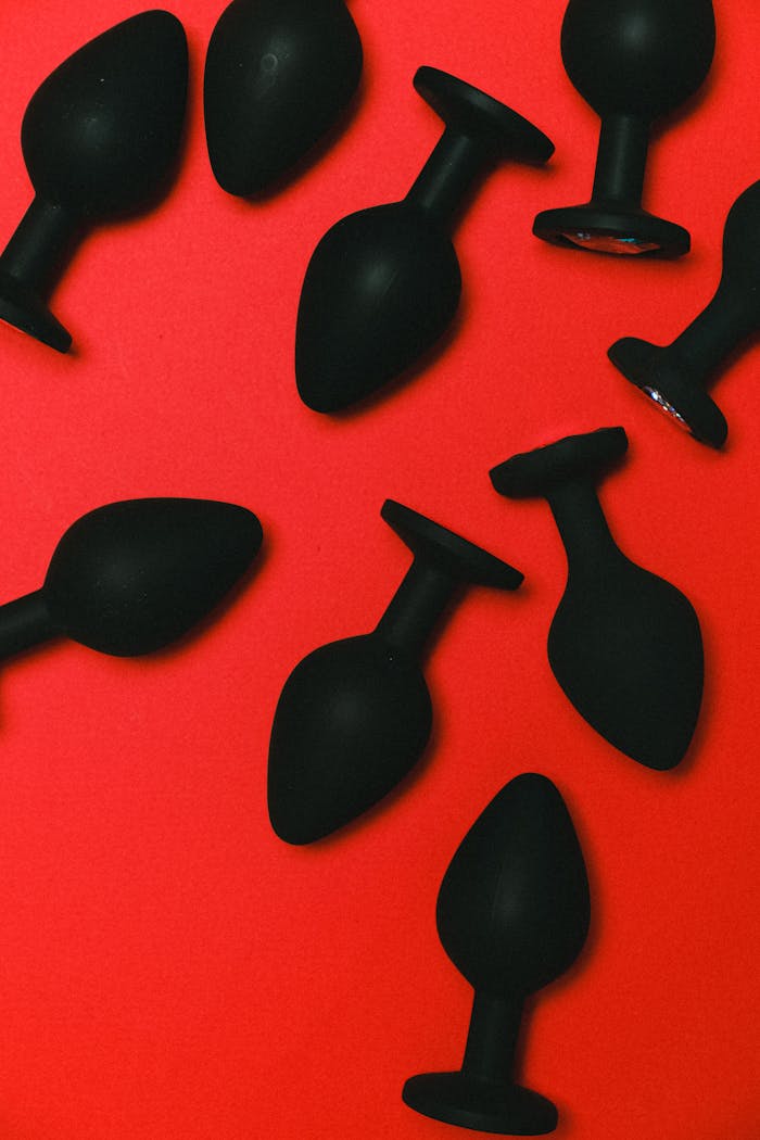 Various black silicone sex toys arranged on a vibrant red backdrop.